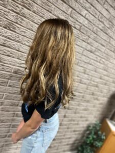 Woman with long wavy hair facing wall.