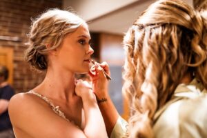 Bride getting makeup applied before wedding ceremony.