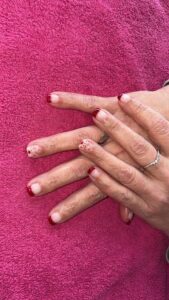 Red-tipped nails on pink towel background.