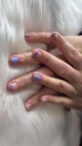 Purple manicured nails on white fur background.