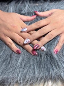 Hands with maroon and white marble nails.