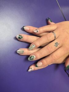 Green-themed nail art with hand tattoo.