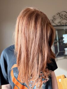 Person with long, straight red hair indoors.
