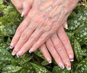 Hands with floral nail art on leaves.