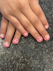 Hands with pink nail polish on nails.