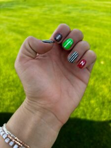 Hand with colorful, themed nail art outdoors.