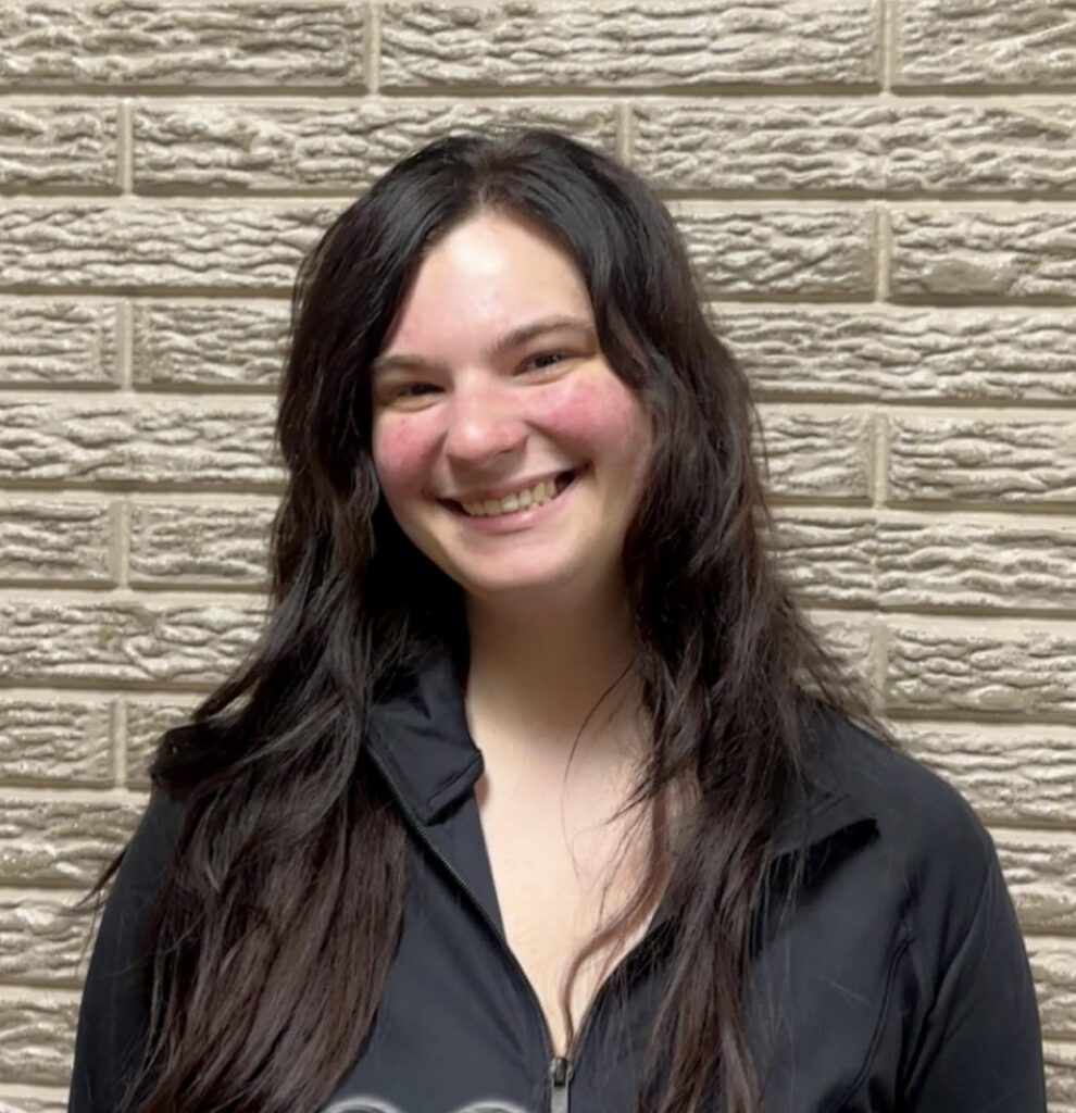 Smiling woman with long dark hair, brick wall